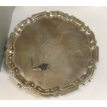 A large Edwardian silver salver with pie crust edge, raised on four hoof feet,