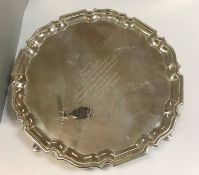 A large Edwardian silver salver with pie crust edge, raised on four hoof feet,