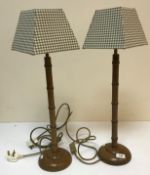 A pair of simulated bamboo table lamps on circular bases, with modern check shades,