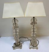 A pair of modern perspex candlesticks as piled books swivelling on a chrome style rod,