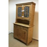 A pine dresser with two frosted glazed doors enclosing two shelves over a recess,