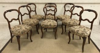 A set of eight Victorian walnut shaped back dining chairs with foliate carved top rail over a