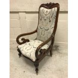 A Victorian mahogany framed scroll arm chair with foliate carved top rail over an upholstered back