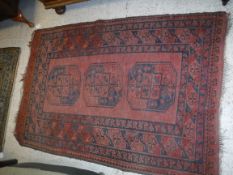 An Afghan rug, the central panel set with three repeating medallions on a blood red ground,