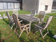 A slatted teak garden table and six folding elbow chairs bearing "Swan Hattersley Garden Furniture"