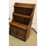 An Ercol elm side cabinet with two open shelves over two panelled cupboard doors, 61 cm wide x 33.