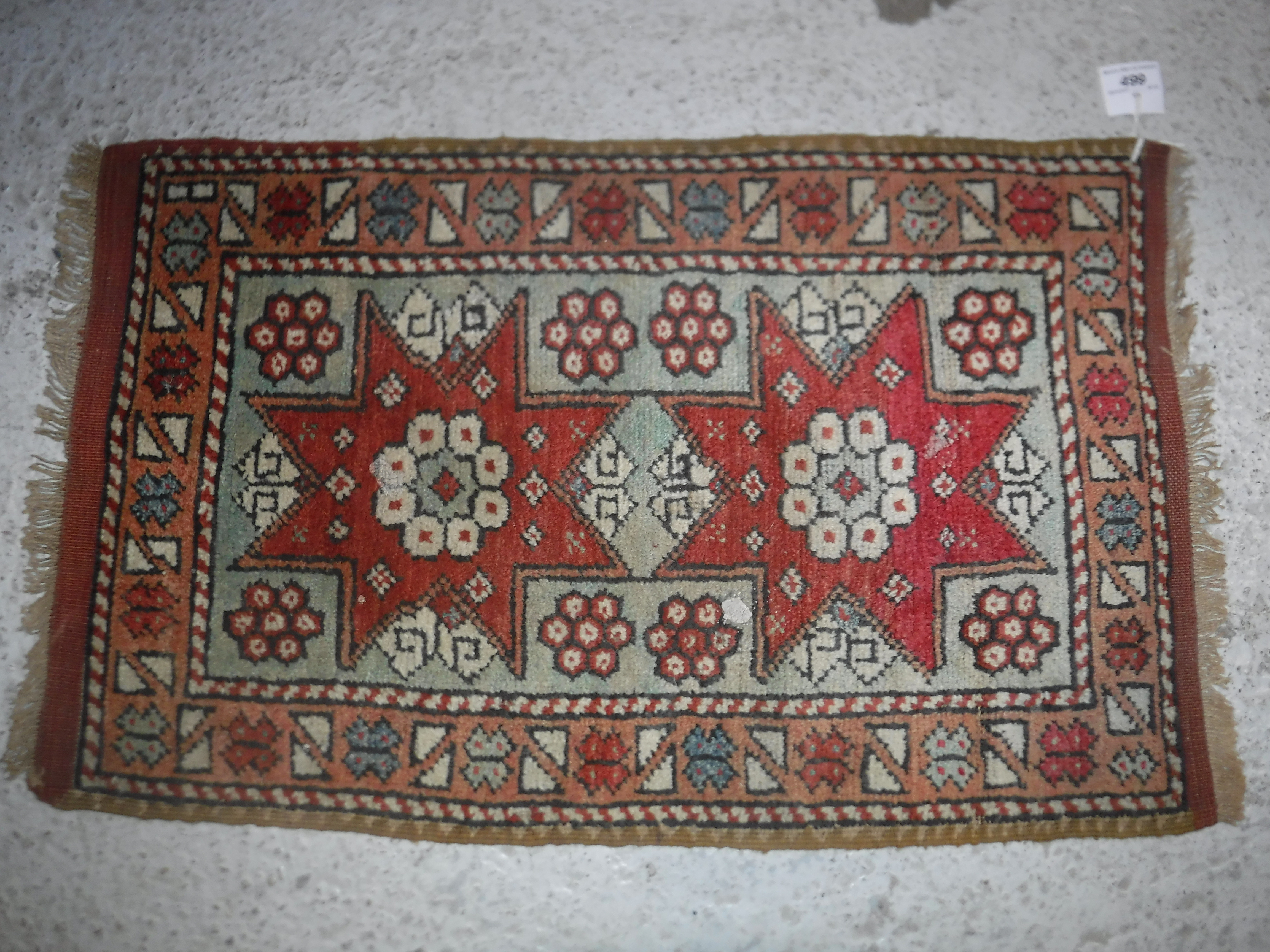 A Caucasian rug, the central panel set with two star shaped medallions on a mint green ground,