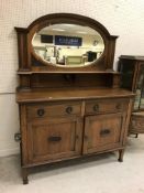 A circa 1900 oak sideboard with mirrored back over two drawers and two cupboard doors on square