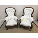 A pair of Victorian spoon back salon chairs with mahogany show frames and buttoned backed cream kid