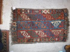 A Caucasian rug, the central panel set with three rows of repeating geometric motifs in red, green,