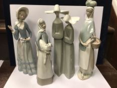 A collection of four Lladro figures including "A group of two nuns", "Girl with basket of fruit",