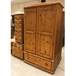 A modern pine wardrobe with two fielded panelled doors over a single drawer,