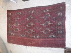 A Bokhara Juval rug, the main panel set with stylised elephant foot medallions on a red ground,