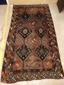 A Caucasian rug, the central panel set with repeating dark blue medallions on a faded purple ground,