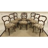 A set of eight Victorian walnut shaped back dining chairs with foliate carved top rail over a