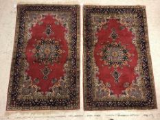 A pair of fine Oriental rugs, the central panels set with floral decorated circular medallion on a