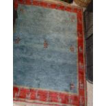 A Gabbeh rug, the central panel set with five stylised animal motifs on a red ground, within a