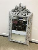 A painted carved wooden framed wall mirror with C scroll decoration and bevel edged rectangular