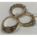 Three 9 carat gold dress rings, one set with opal, another with aquamarine and the other red and