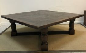 A modern oak coffee table in the 17th Century manner, the square top with cleated ends, raised on
