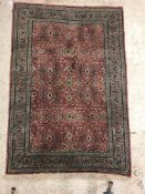 A Persian rug, the central panel set with all-over floral decoration on a pink ground, within a