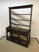 A 19th Century oak dresser, the three tier open plate rack with iron cup hooks over three drawers on