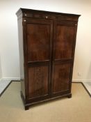 An Edwardian mahogany two door wardrobe, the twin panelled figured doors enclosing a single