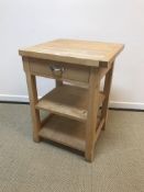 A modern beech veneered butcher's block type table with single drawer above two shelves on chamfered
