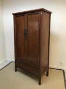 A 20th Century Chinese cherry wood two door wardrobe of tapering form, raised on plain rounded