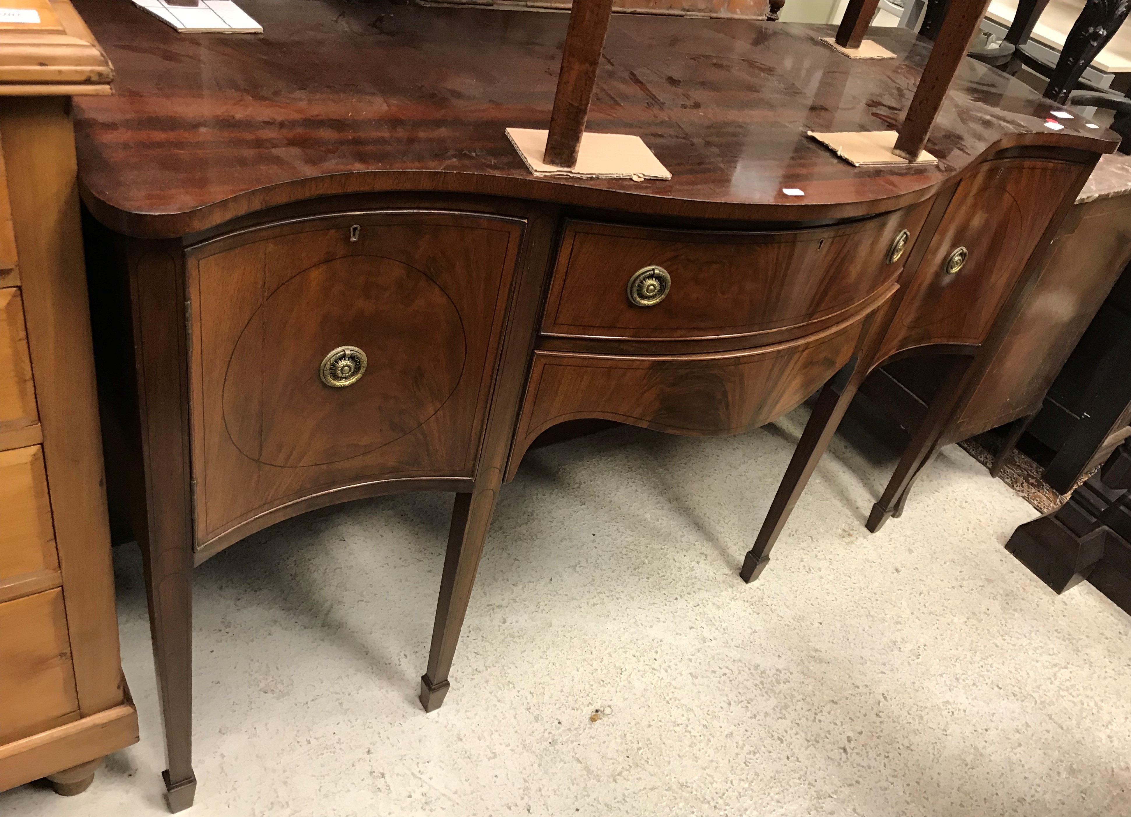 An Edwardian mahogany serpentine fronted sideboard in the George III taste, the plain top over two