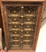 A Middle Eastern carved and painted teak door of small proportions, 52 cm x 92 cm within a carved