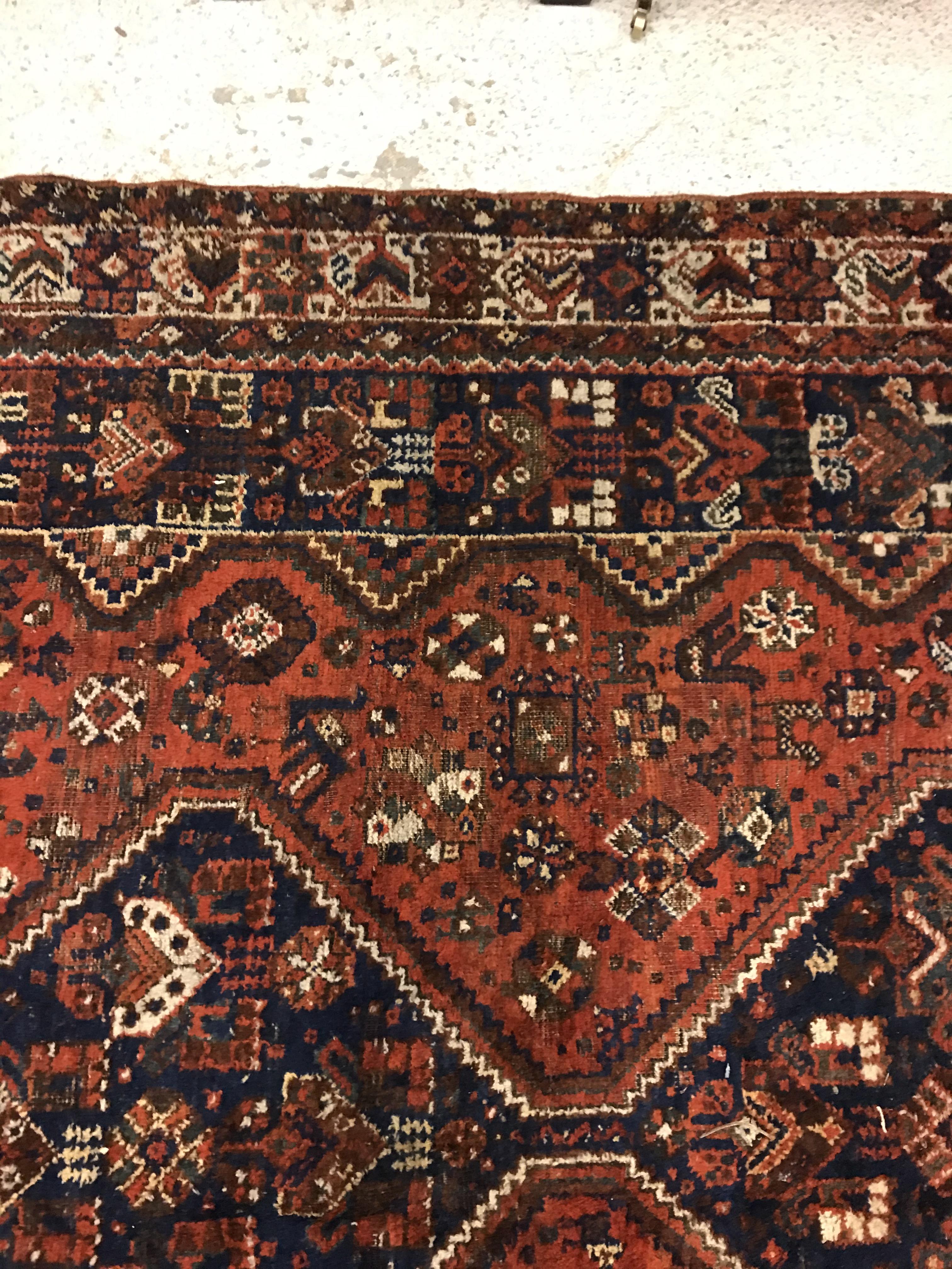 A Shiraz carpet, the central panel set with three joined diamond shaped medallions on a red and blue - Image 8 of 17