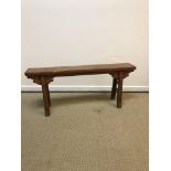 A Chinese elm bench, the single plank top with foliate carved capped square splayed supports