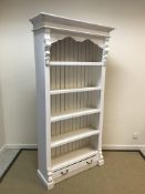 A French Rococo style painted open bookcase with adjustable shelving over a single drawer on