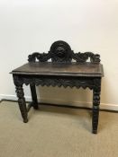 A Victorian carved oak Gothic Revival side table, the raised back with grotesque mask or sunburst