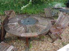 A slatted circular garden table with marble insert and five various slatted folding garden chairs