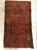 An Afghan prayer rug, the central panel set with stylised tree and pillar decoration on a red