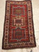 A Kasak runner, the central panel set with three repeating square medallions on a red ground