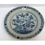An early 19th Century Dutch Delft charger decorated in the Chinese taste with flowers and fence,