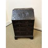A Victorian carved oak bureau of small proportions, the flower head patterae and linen drape