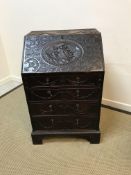 A Victorian carved oak bureau of small proportions, the flower head patterae and linen drape