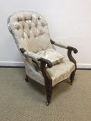 A Victorian mahogany framed buttoned upholstered open arm chair with lotus leaf carved scroll arms