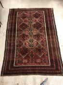 A Caucasian carpet, the central panel set with repeating medallion decoration on a blood red