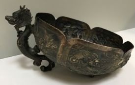An Oriental white metal bowl with embossed dragon and foliate decoration and dragon foot (two others