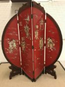 A 20th Century red lacquered and shibyama inlaid four fold screen of circular form, raised on carved