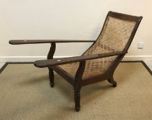 A 19th Century Colonial rosewood plantation type chair with caned seat and elongated arms on lotus