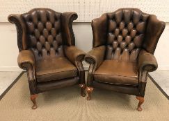 Two similar modern leather upholstered armchairs, each with buttoned back, raised on cabriole legs