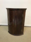 A 19th Century North Country English oak and cross-banded bow fronted corner cupboard with two