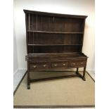 A late 18th Century oak dresser, the boarded two tier plate rack with moulded cornice above two