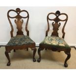 Two very similar George I walnut dining chairs with shell carved and bow decorated top rail over a